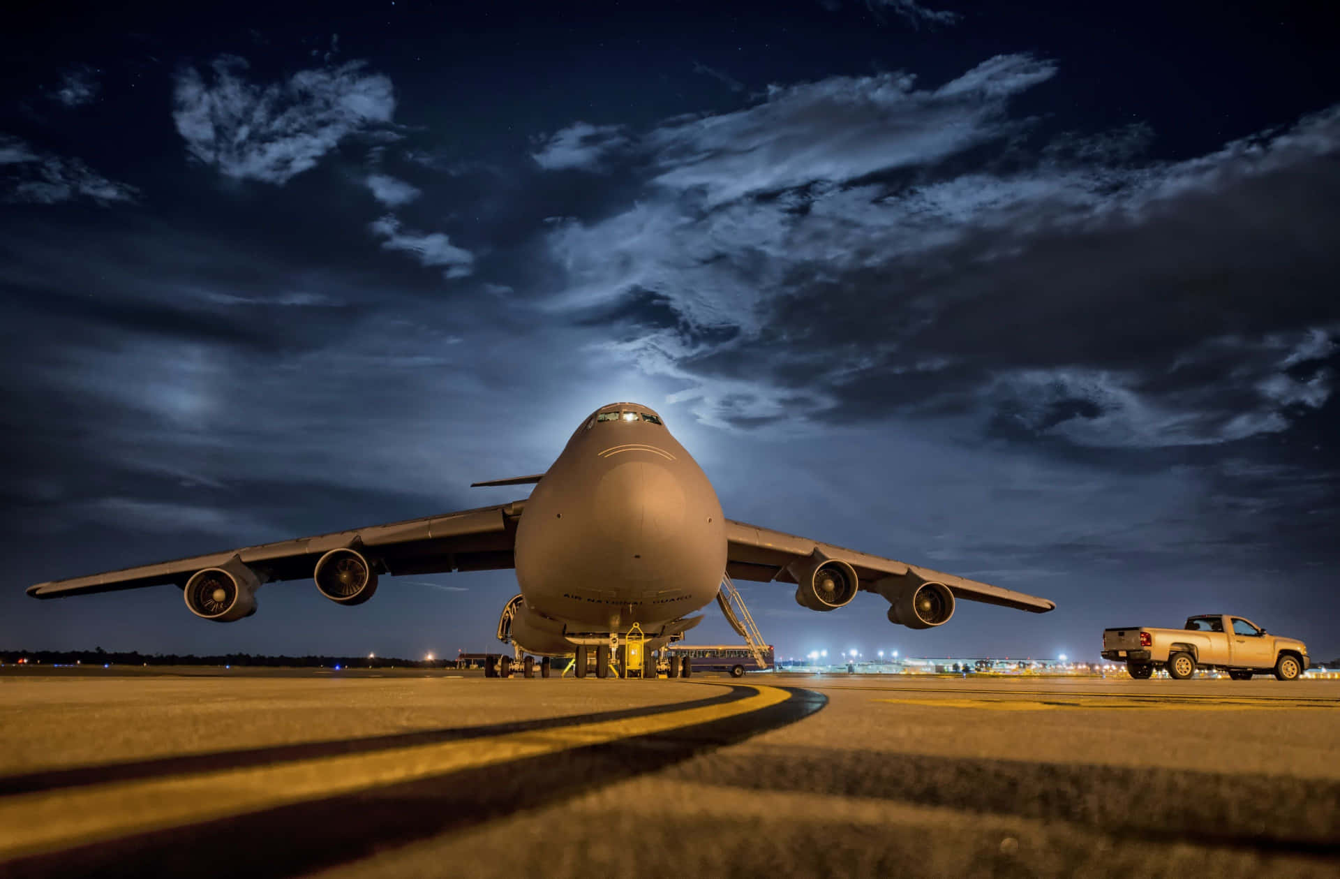 A Large Military Aircraft On The Runway At Night Background