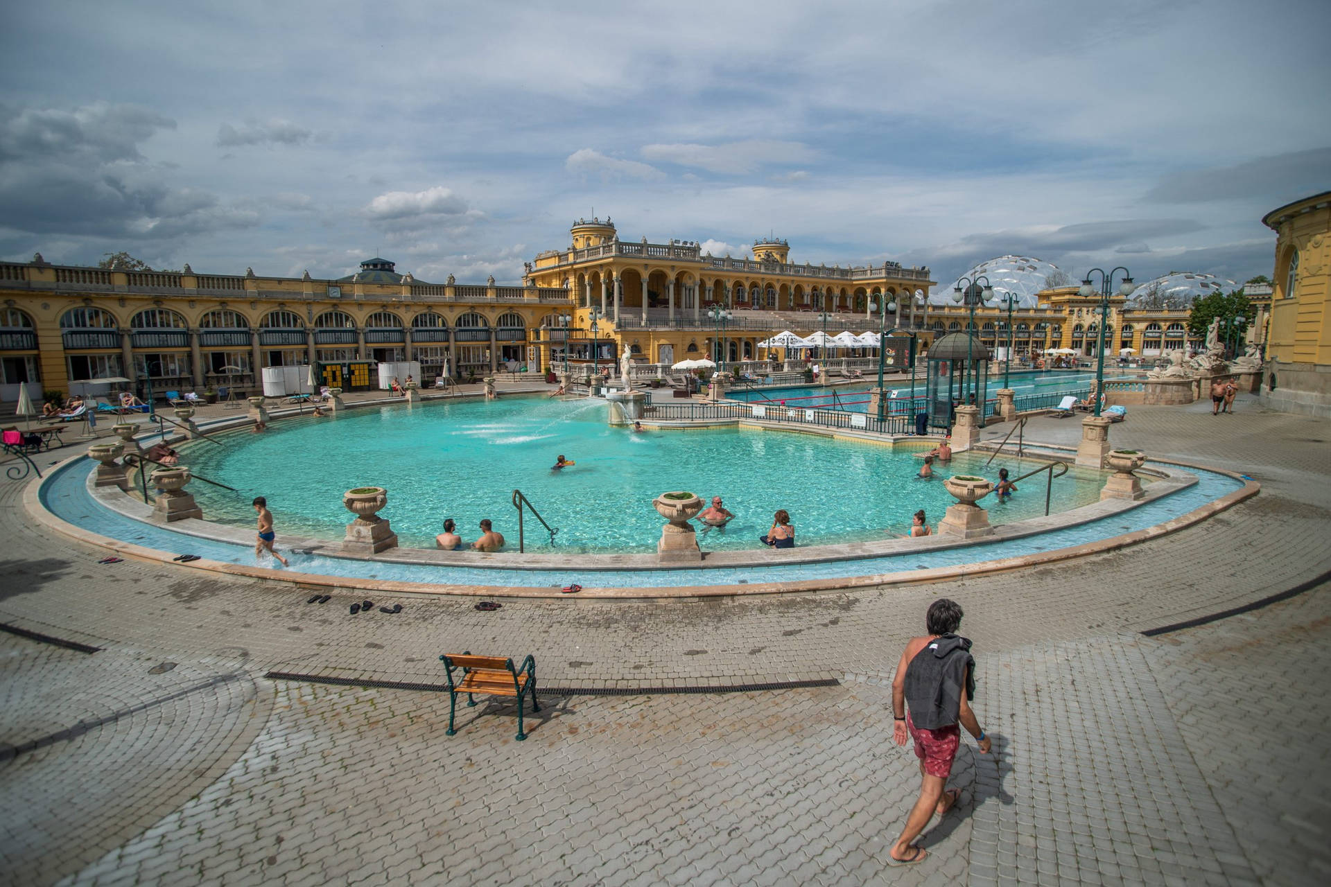 A Large Pool With People Walking Around It Background