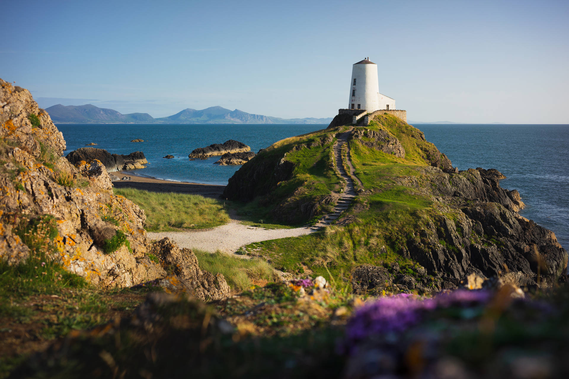 A Lighthouse Sits On Top Of A Rocky Cliff Background