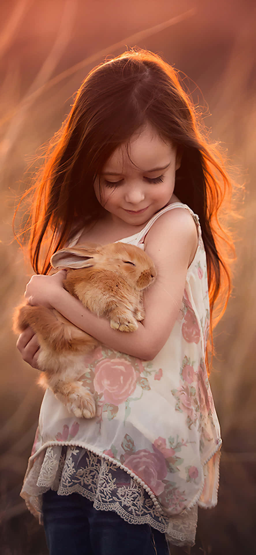 A Little Girl Holding A Rabbit In The Field Background