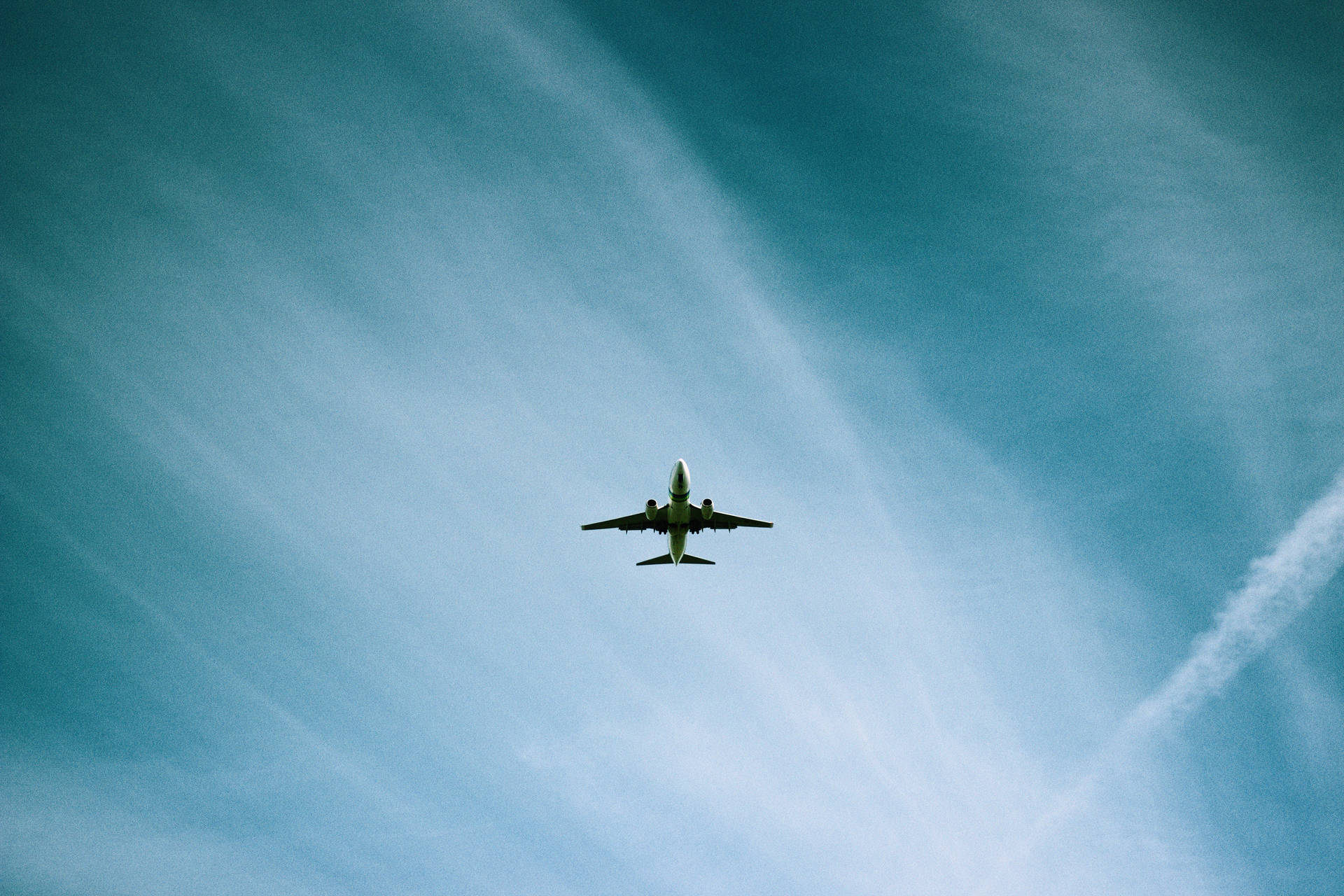 A Low Angle View Of A Plane Flying Through The Sky Background