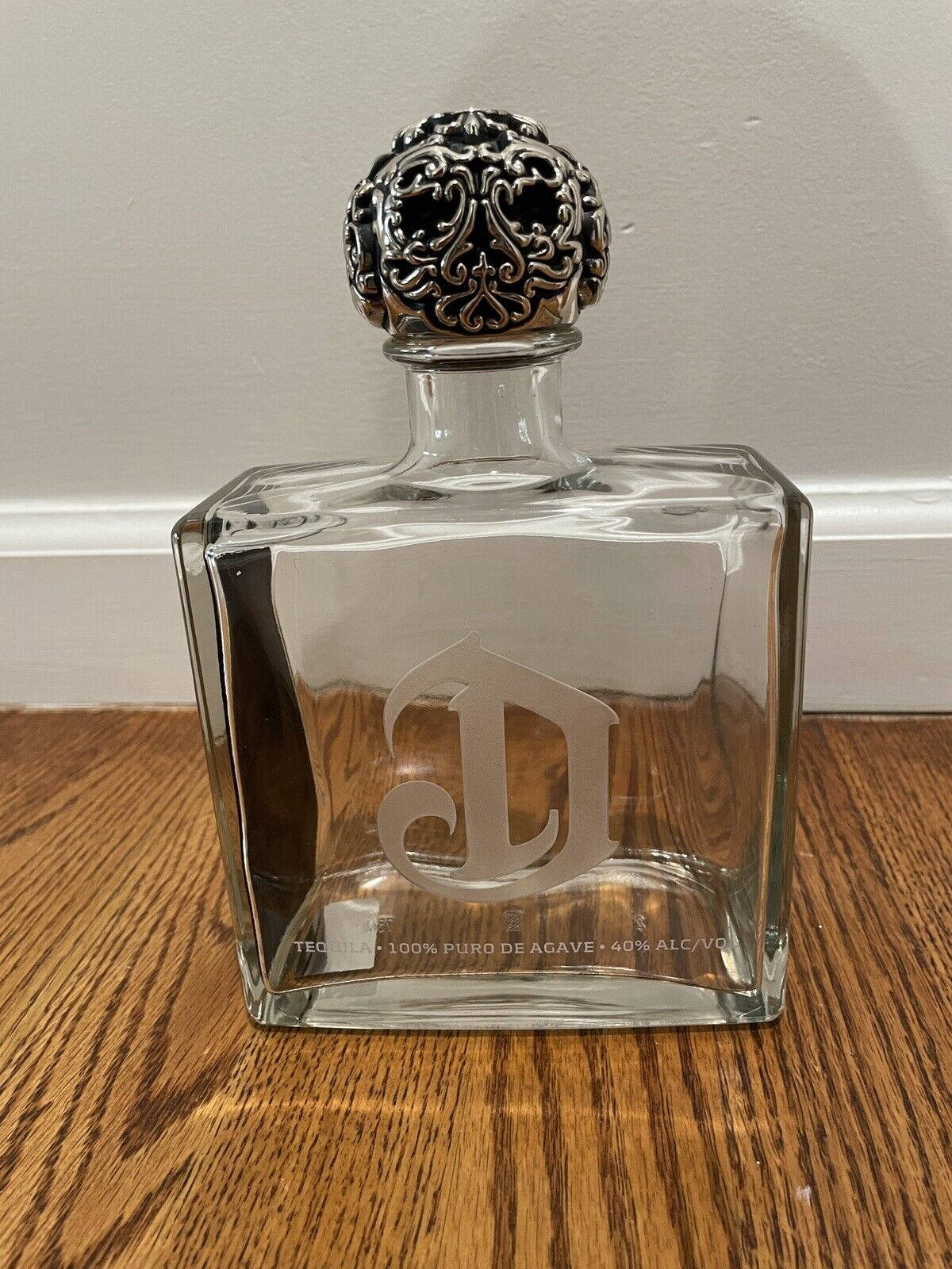 A Luxurious Deleon Tequila Bottle Elegantly Poised On A Wooden Surface.