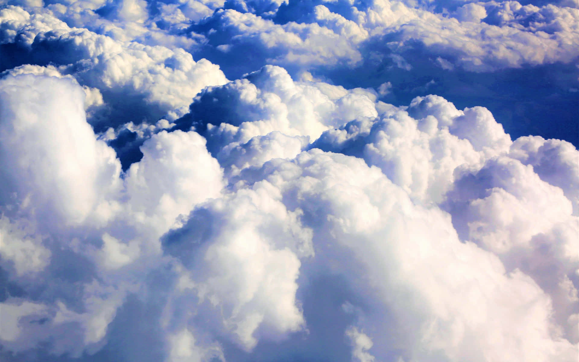 A Majestic Aerial View Of Fluffy Clouds In A Vibrant Blue Sky. Background