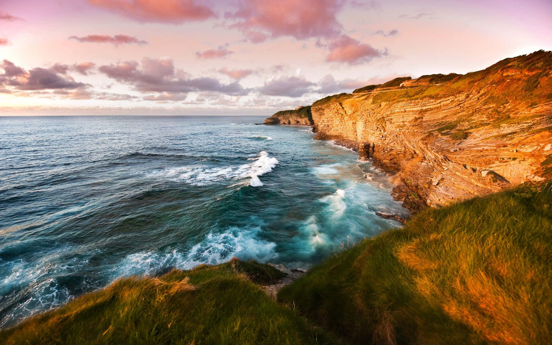 A Majestic Coastal Scene Under A Pink-clouded Sky Background