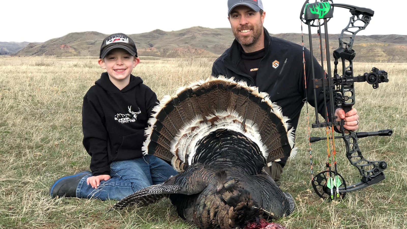 A Man And A Boy Pose With A Turkey Background