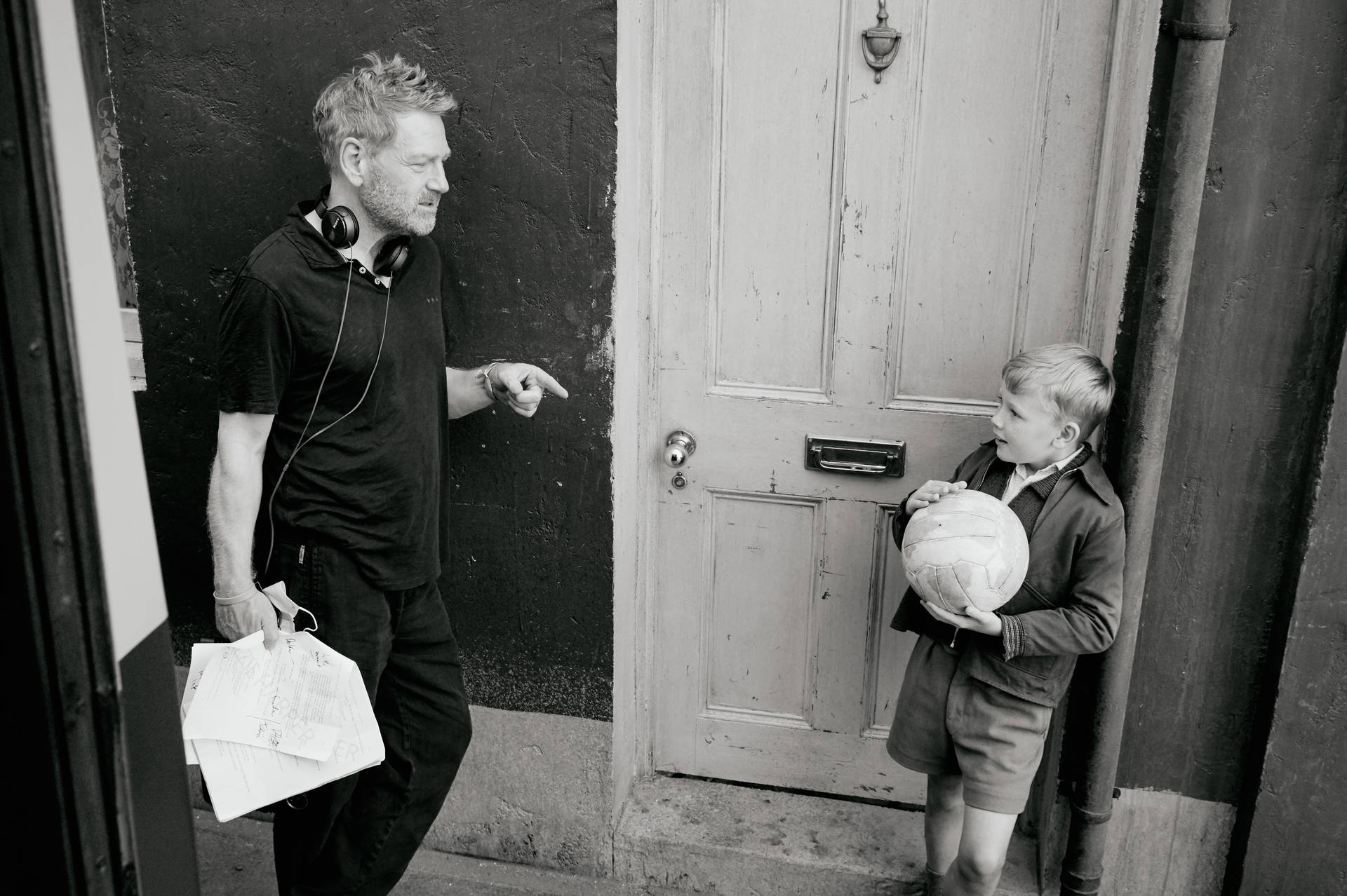 A Man And A Boy Standing Outside A Door