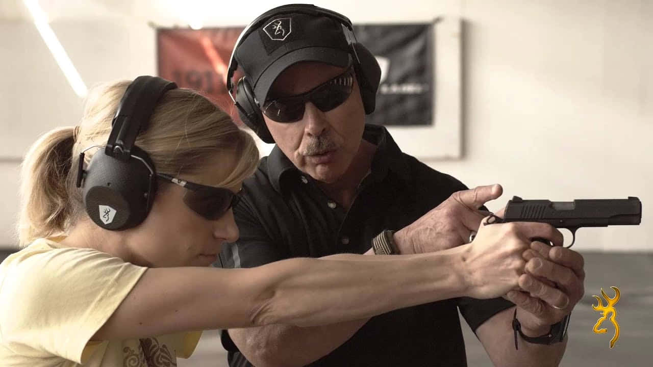 A Man And Woman Are Holding A Gun Background