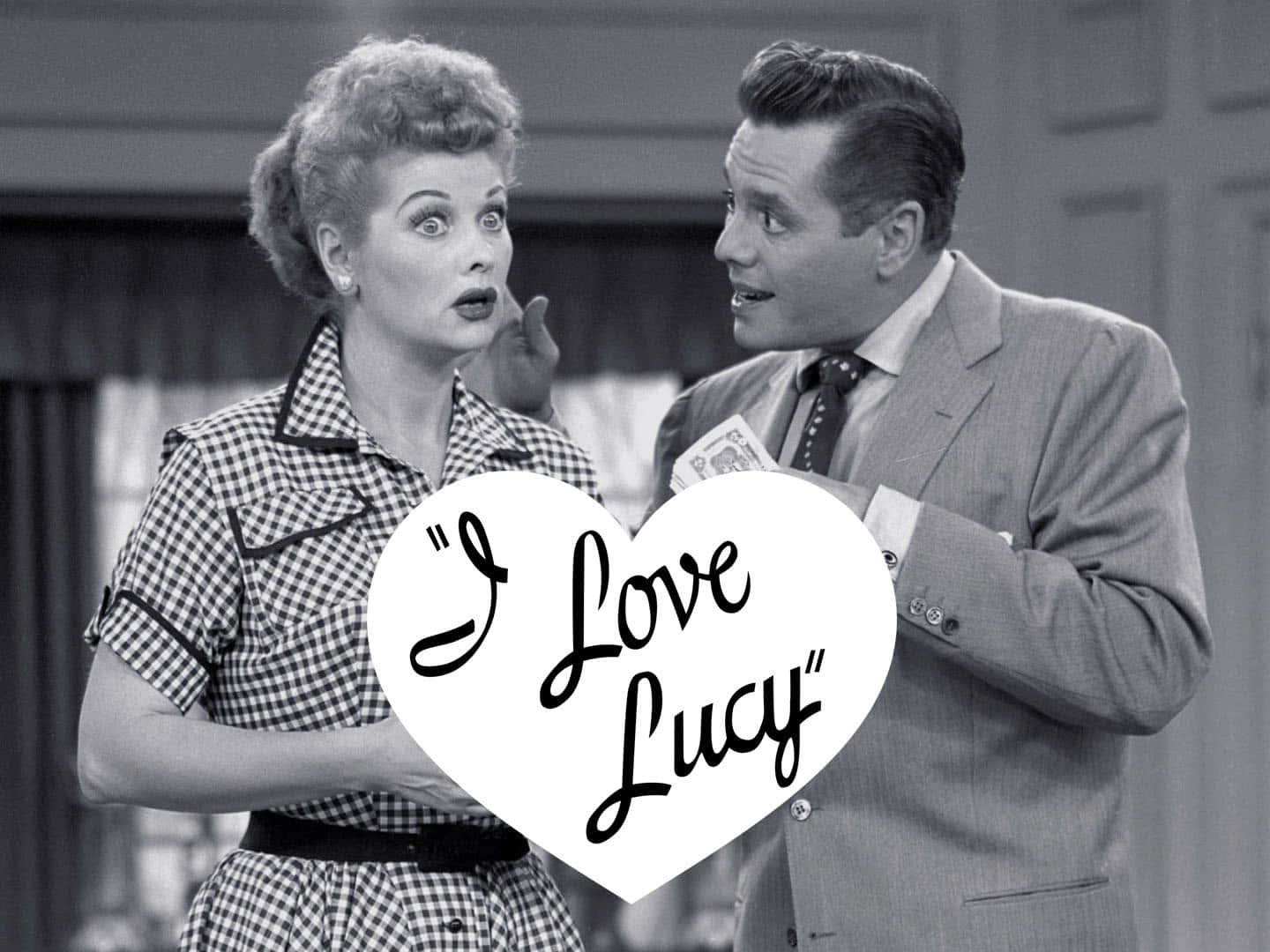 A Man And Woman Holding A Sign That Says I Love Lucy Background