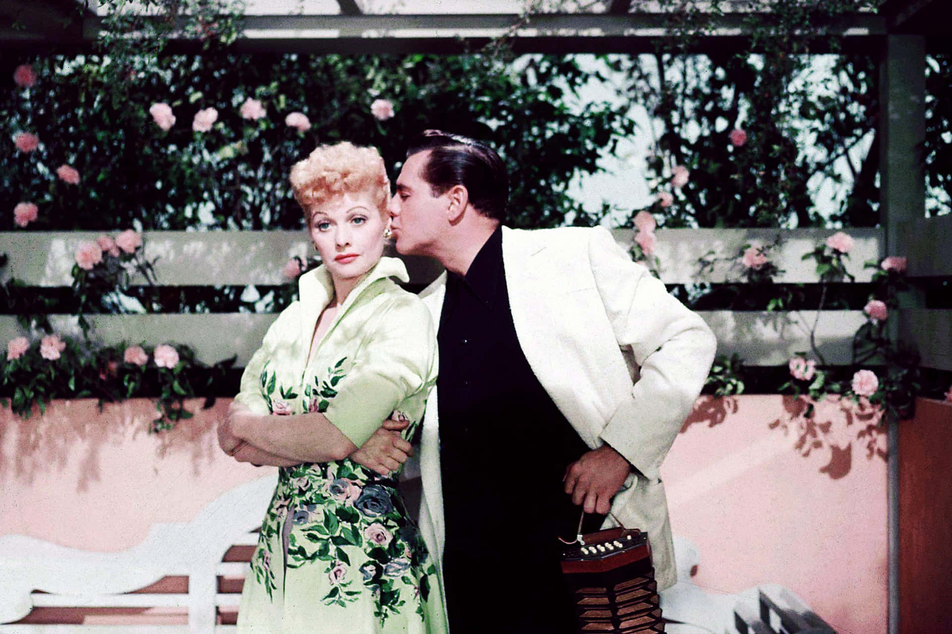 A Man And Woman Kissing In Front Of A Flower Garden