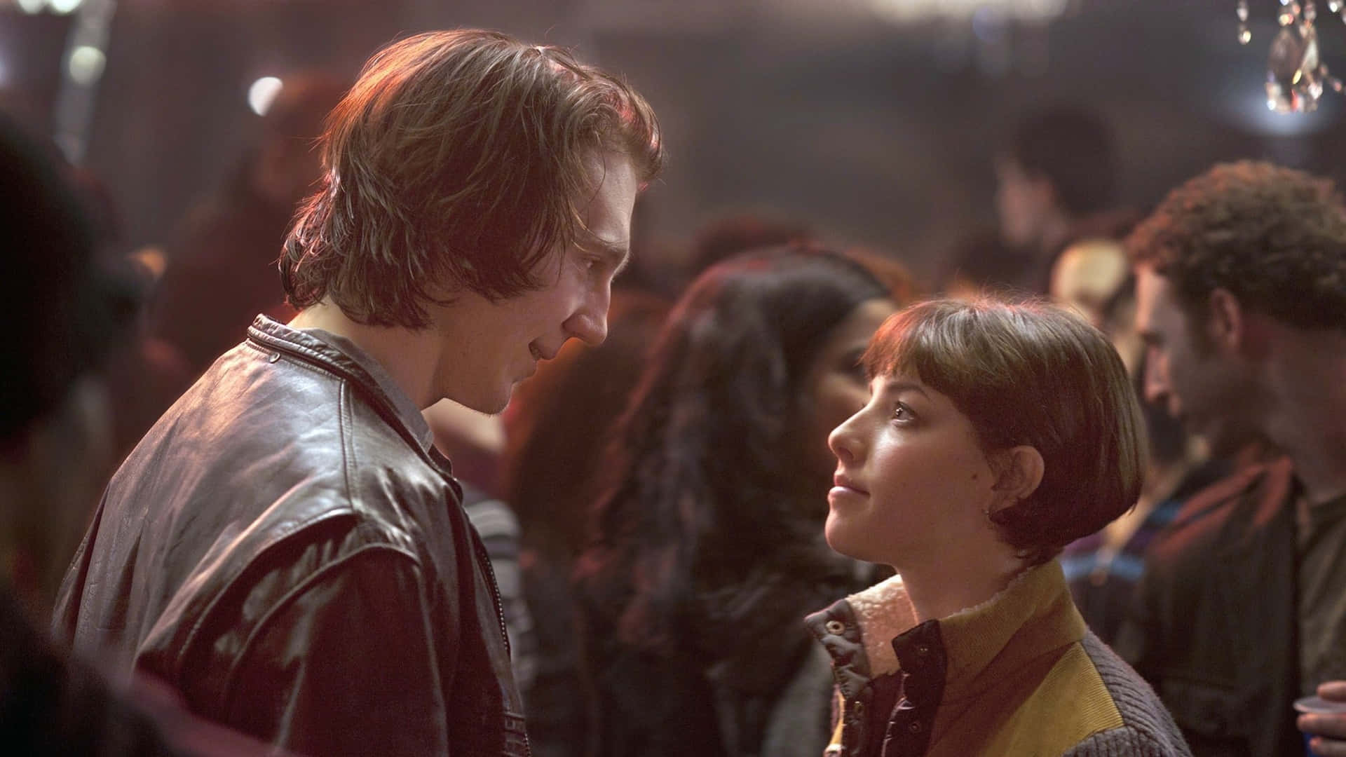 A Man And Woman Standing In A Crowd Background