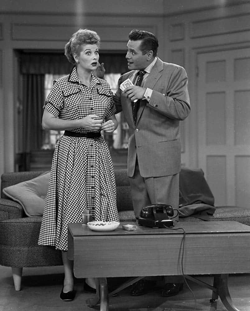 A Man And Woman Standing In Front Of A Couch Background