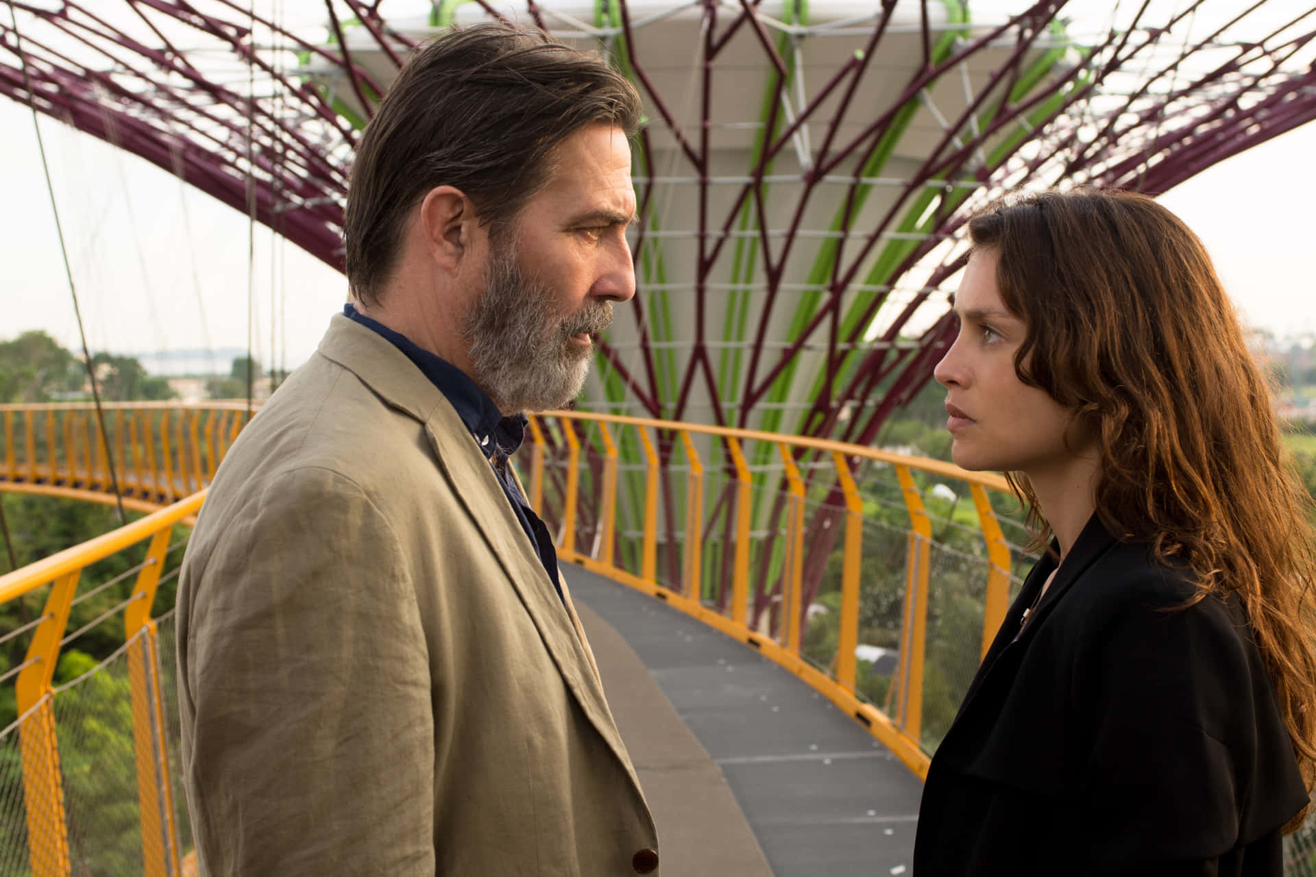 A Man And Woman Standing Next To Each Other On A Bridge Background