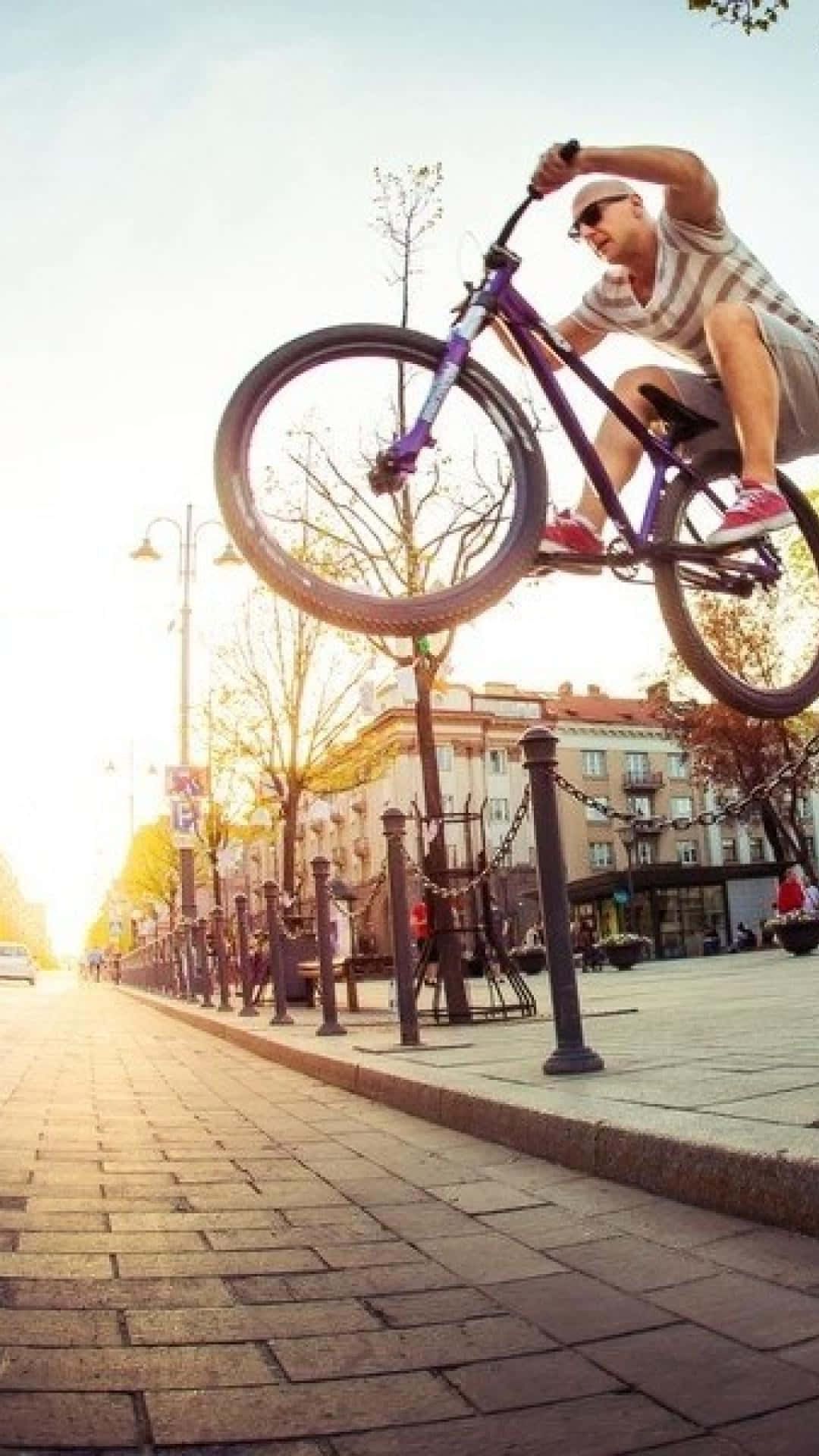 A Man Doing A Bike Trick In The City Background