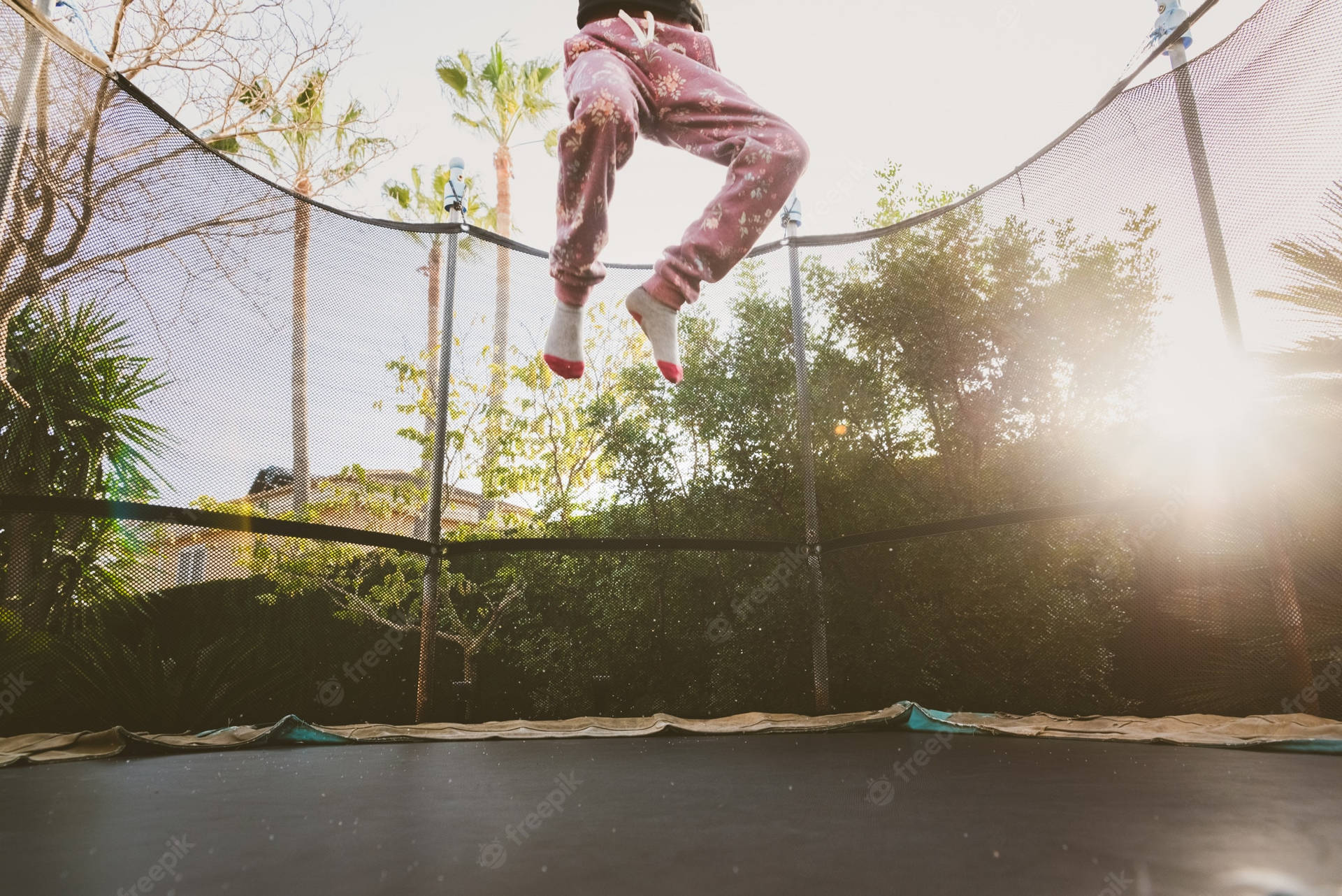 A Man Finds Joy In Mid-air While Jumping On A Trampoline Background