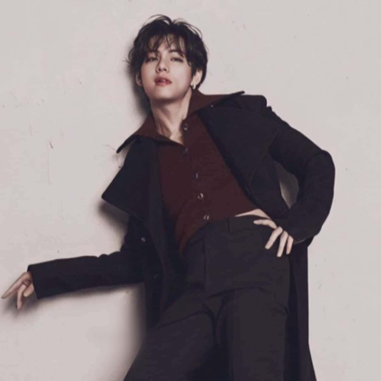 A Man In A Black Coat Leaning Against A Wall Background