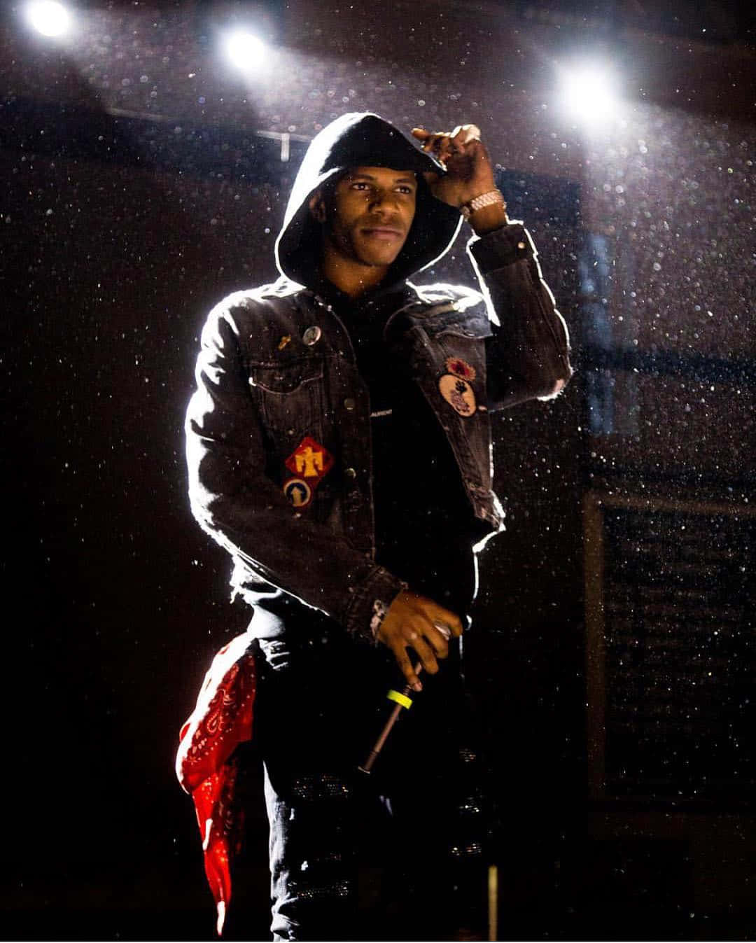 A Man In A Black Jacket Standing In The Rain Background
