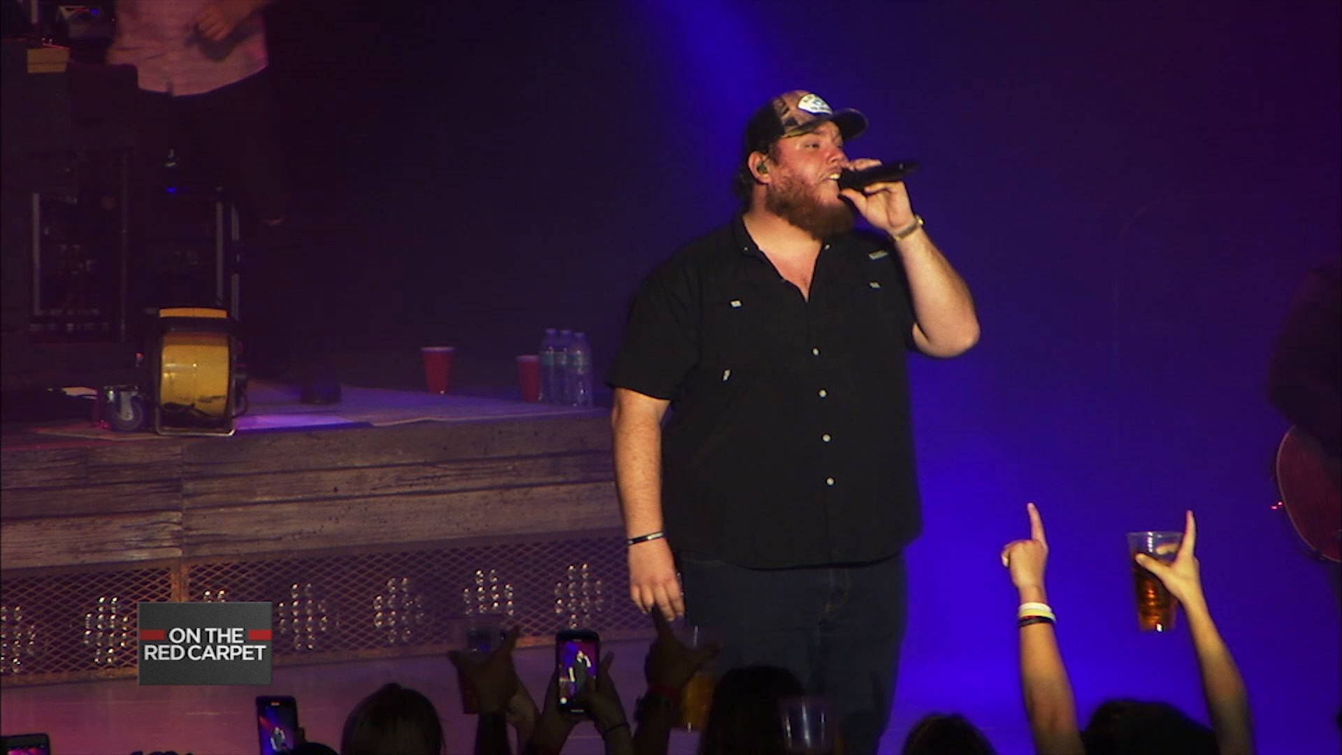 A Man In A Black Shirt Singing Into A Microphone Background