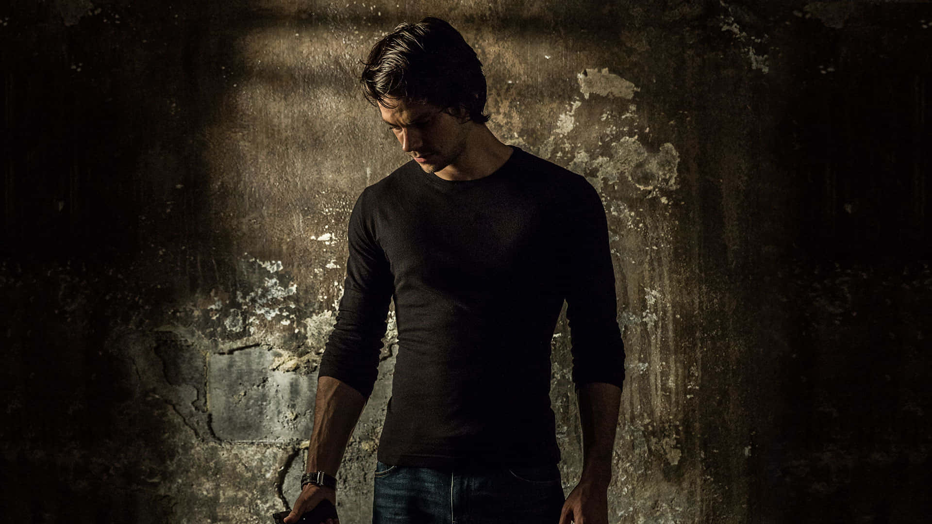 A Man In A Black Shirt Standing In Front Of A Wall Background