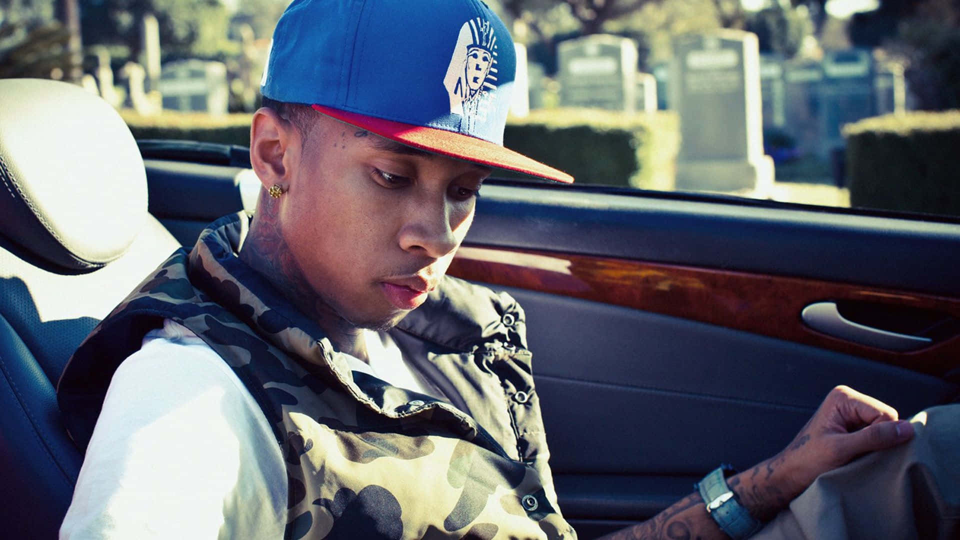 A Man In A Blue Cap Sitting In A Car Background