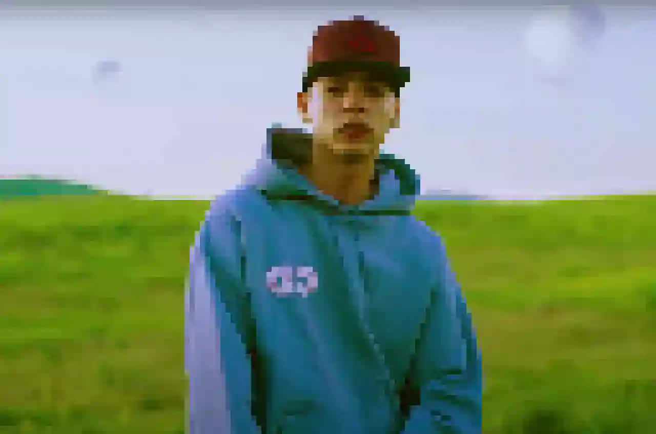 A Man In A Blue Hoodie Standing In A Field Background