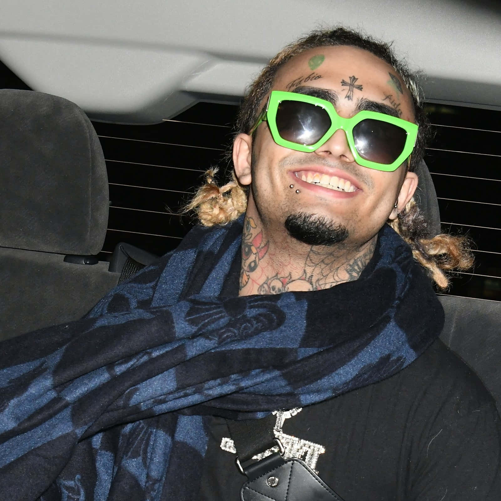 A Man In A Car With Sunglasses And A Scarf