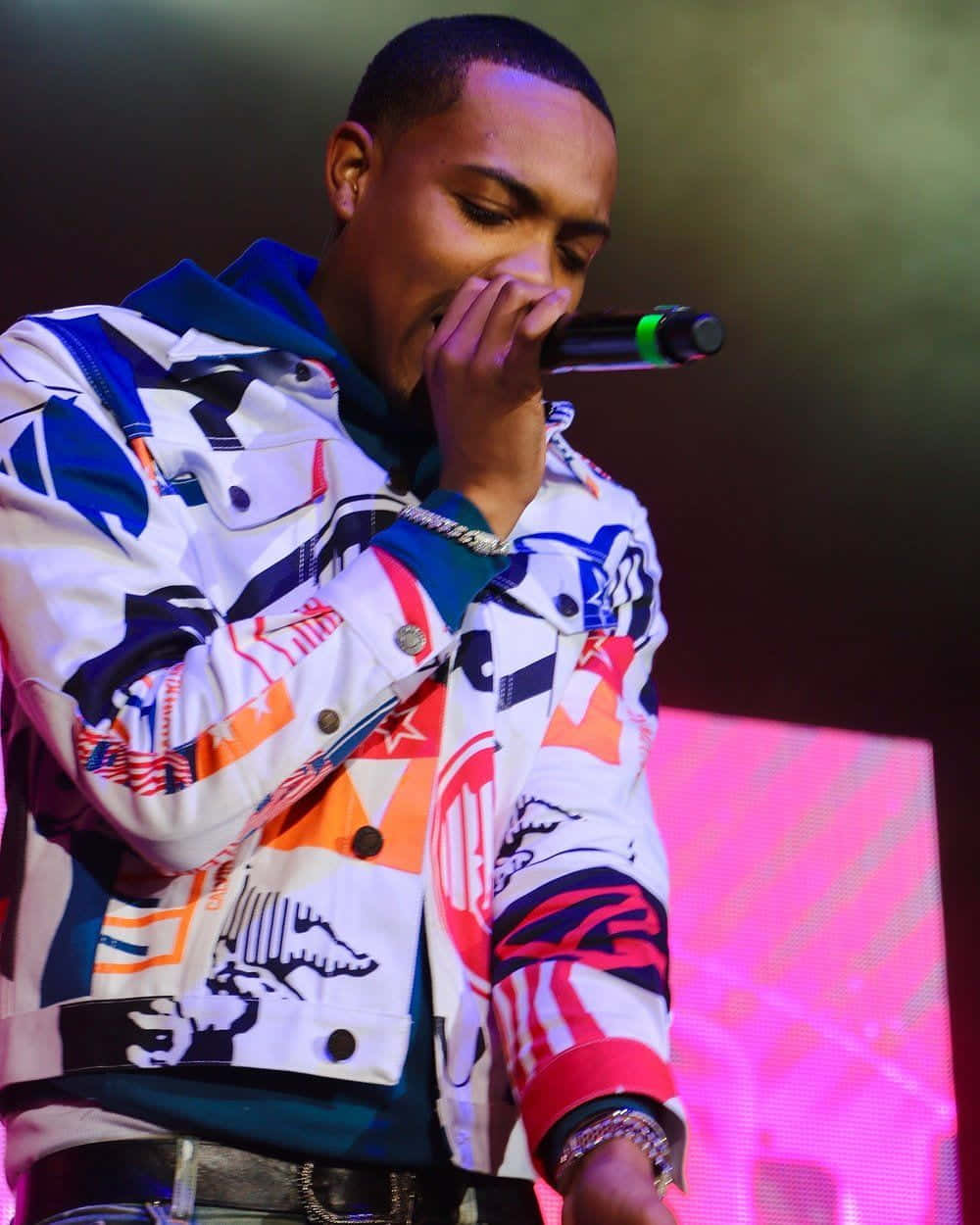 A Man In A Colorful Jacket Singing Into A Microphone