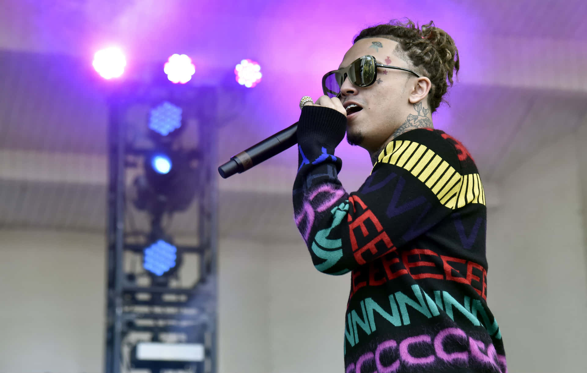 A Man In A Colorful Sweater Is Singing Into A Microphone