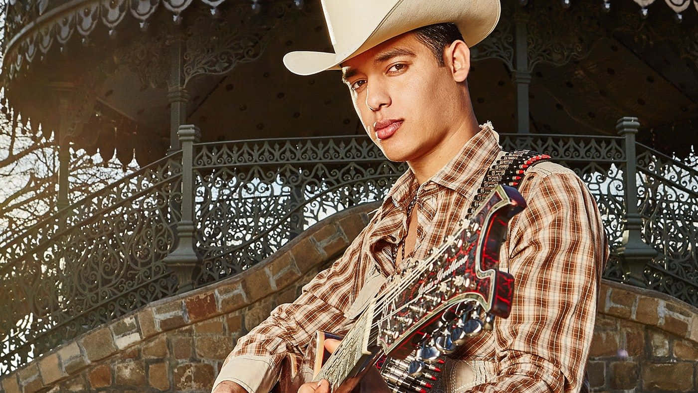A Man In A Cowboy Hat Is Holding A Guitar Background