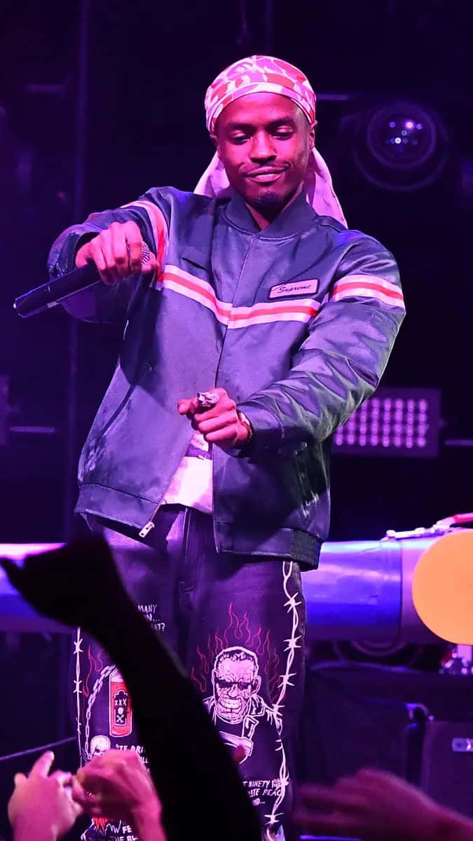 A Man In A Green Jacket Standing On Stage Background