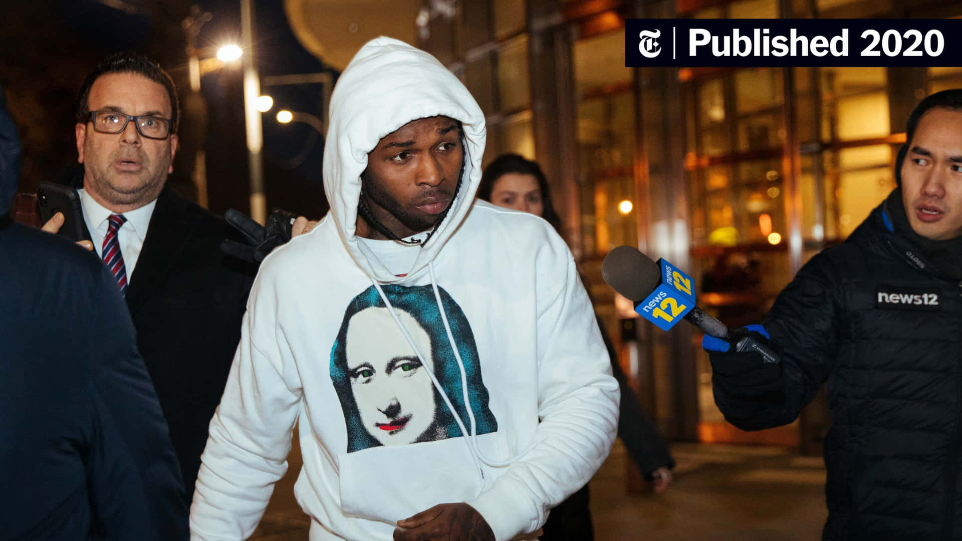 A Man In A Hoodie Is Walking Down The Street Background