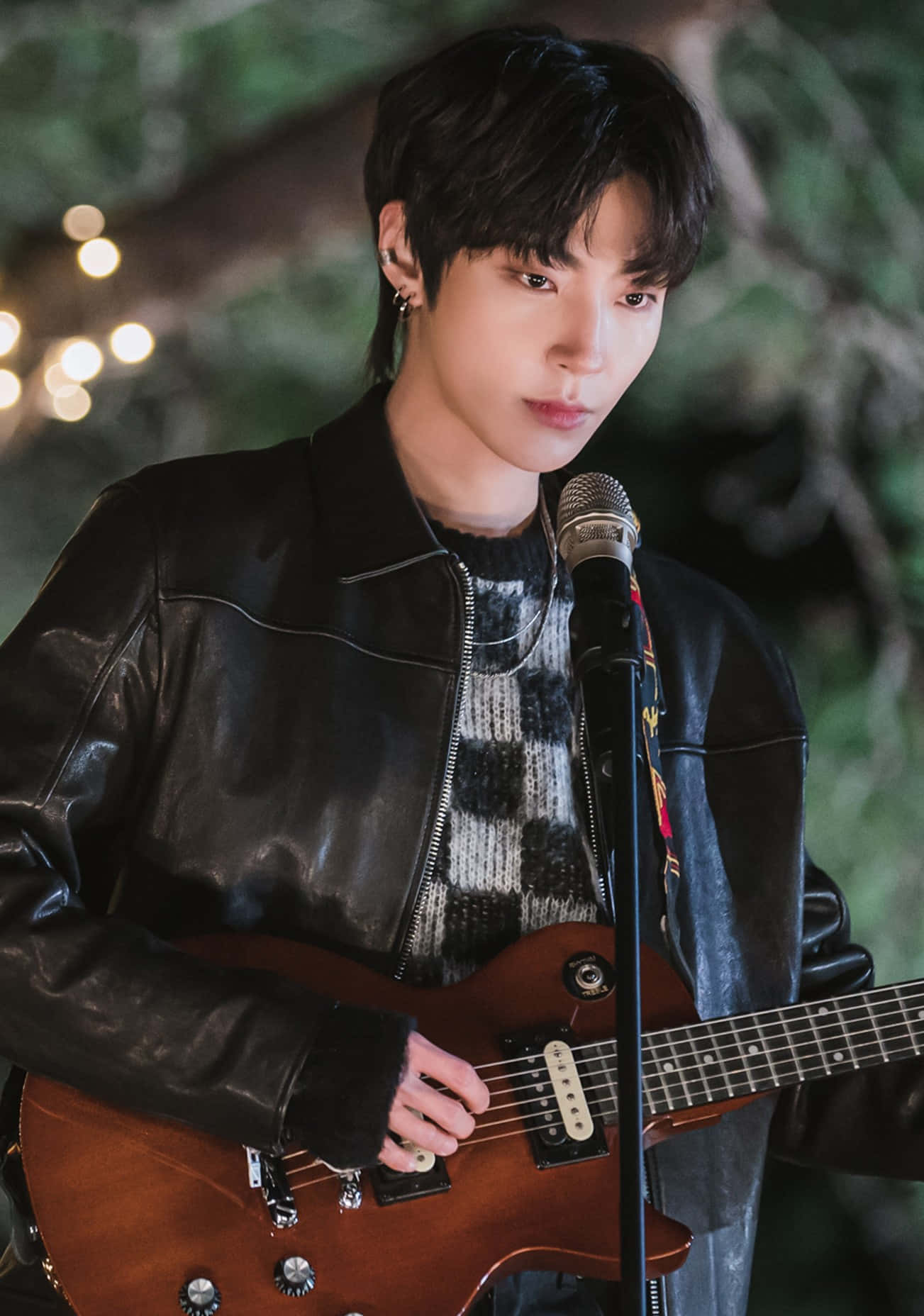 A Man In A Leather Jacket Is Playing A Guitar Background