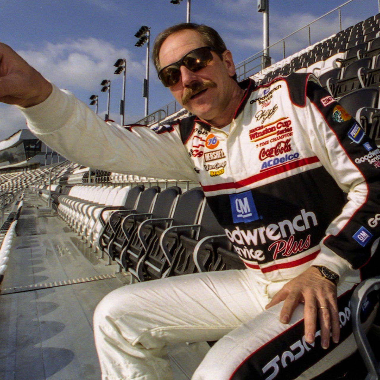 A Man In A Nascar Uniform Is Sitting On A Bench