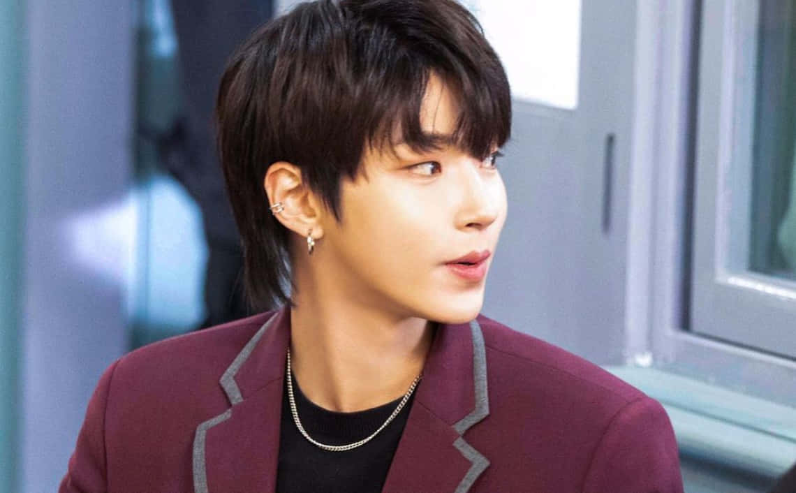A Man In A Purple Jacket Is Looking At Something Background