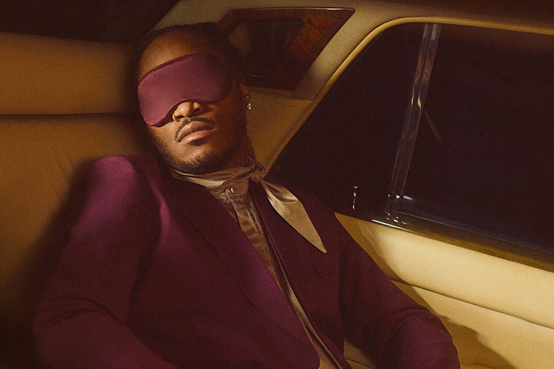 A Man In A Purple Suit Sitting In A Car Background