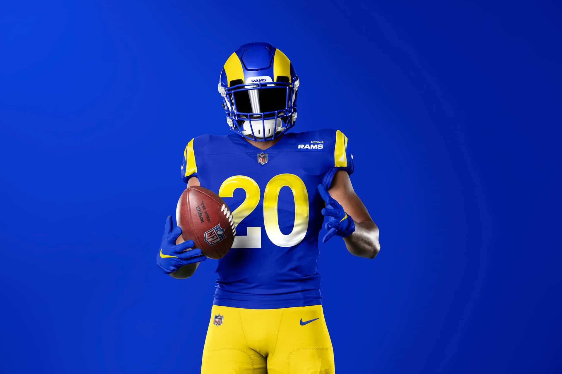 A Man In A Rams Uniform Holding A Football Background