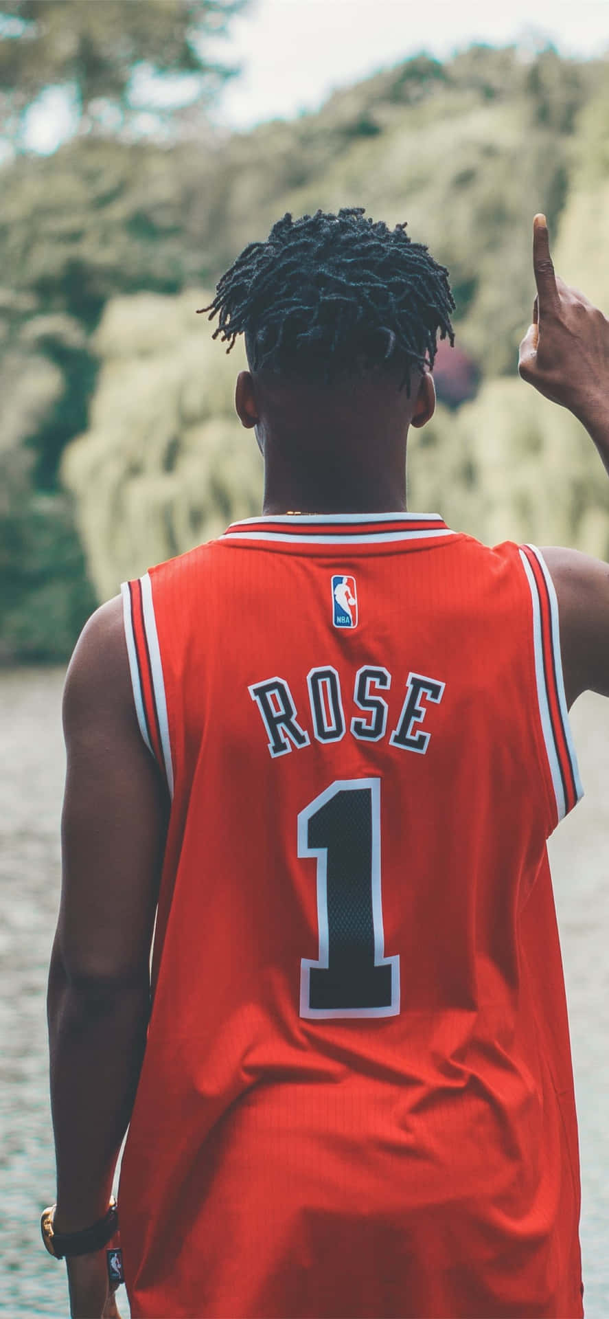 A Man In A Red Jersey Is Pointing To The Water Background