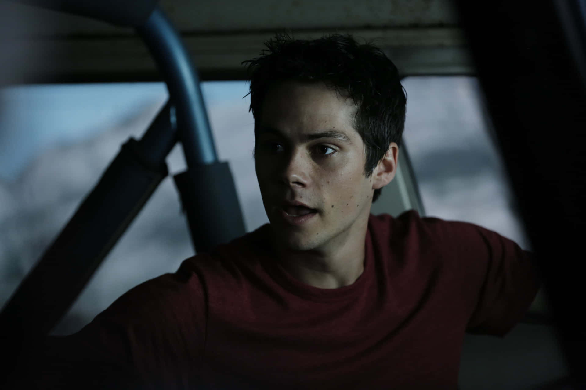A Man In A Red Shirt Is Sitting In A Car Background