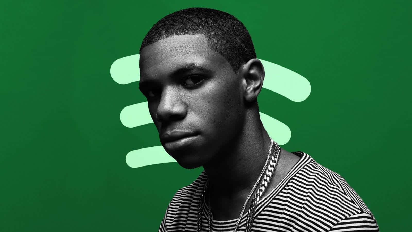 A Man In A Striped Shirt Is Standing In Front Of A Green Background Background