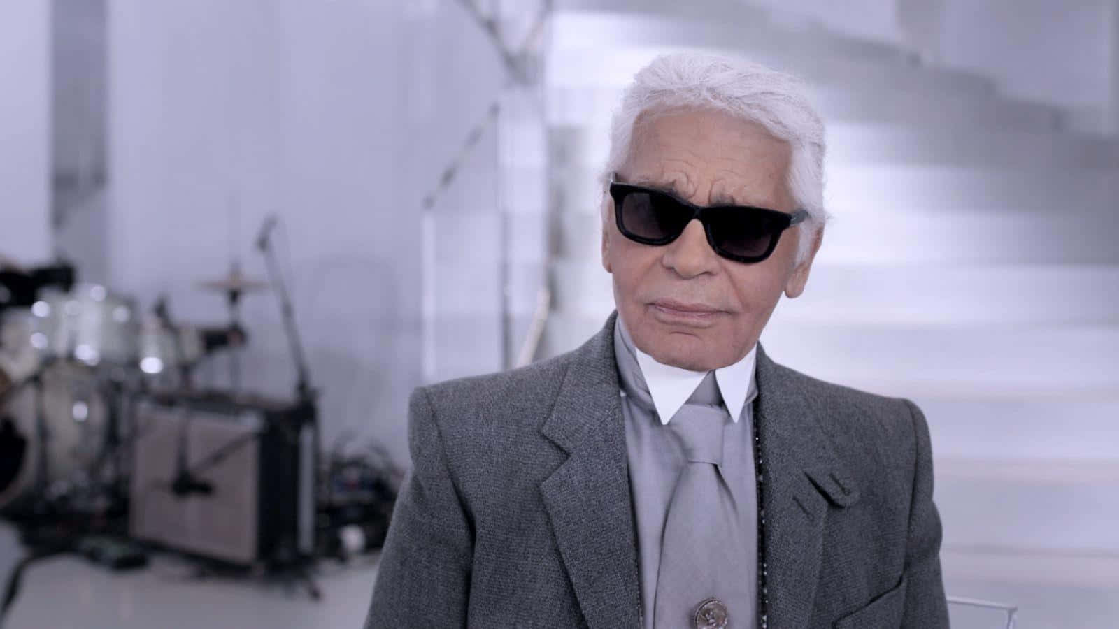 A Man In A Suit And Sunglasses Is Standing In Front Of A Stage Background