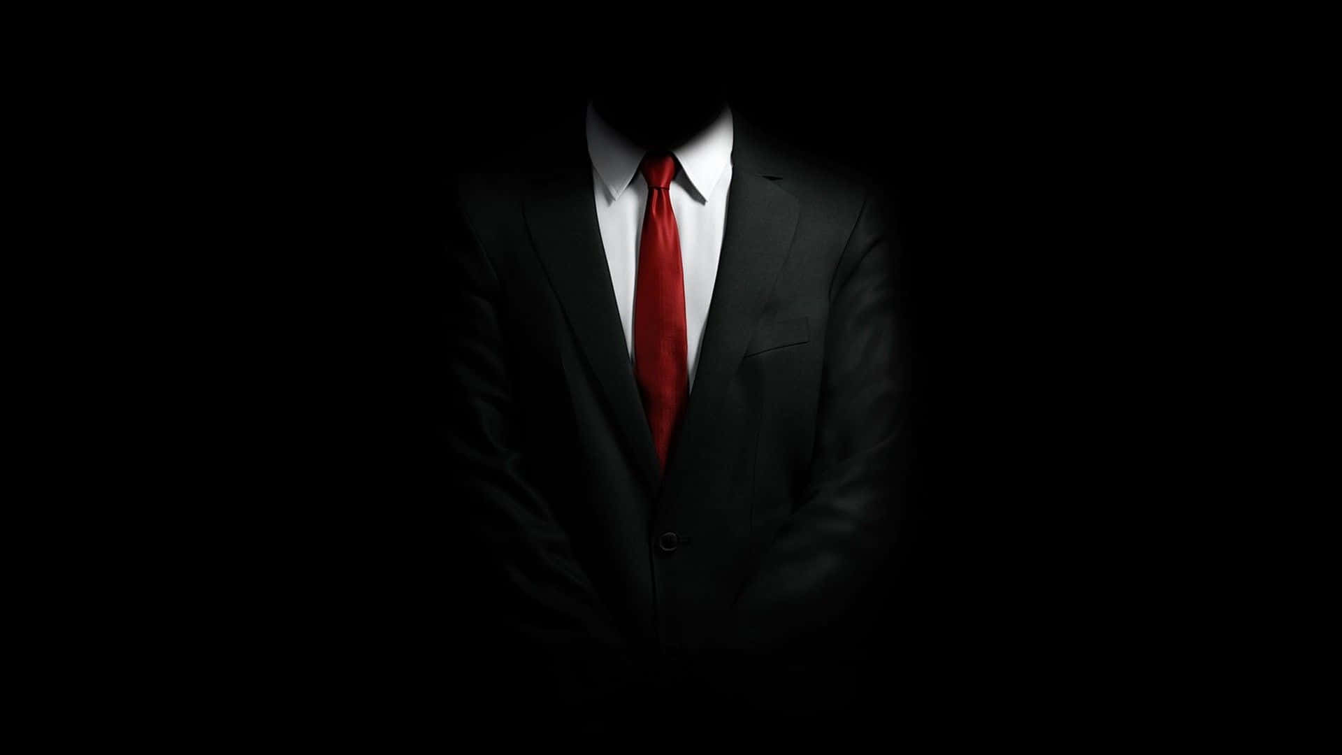 A Man In A Suit And Tie Is Standing In The Dark Background