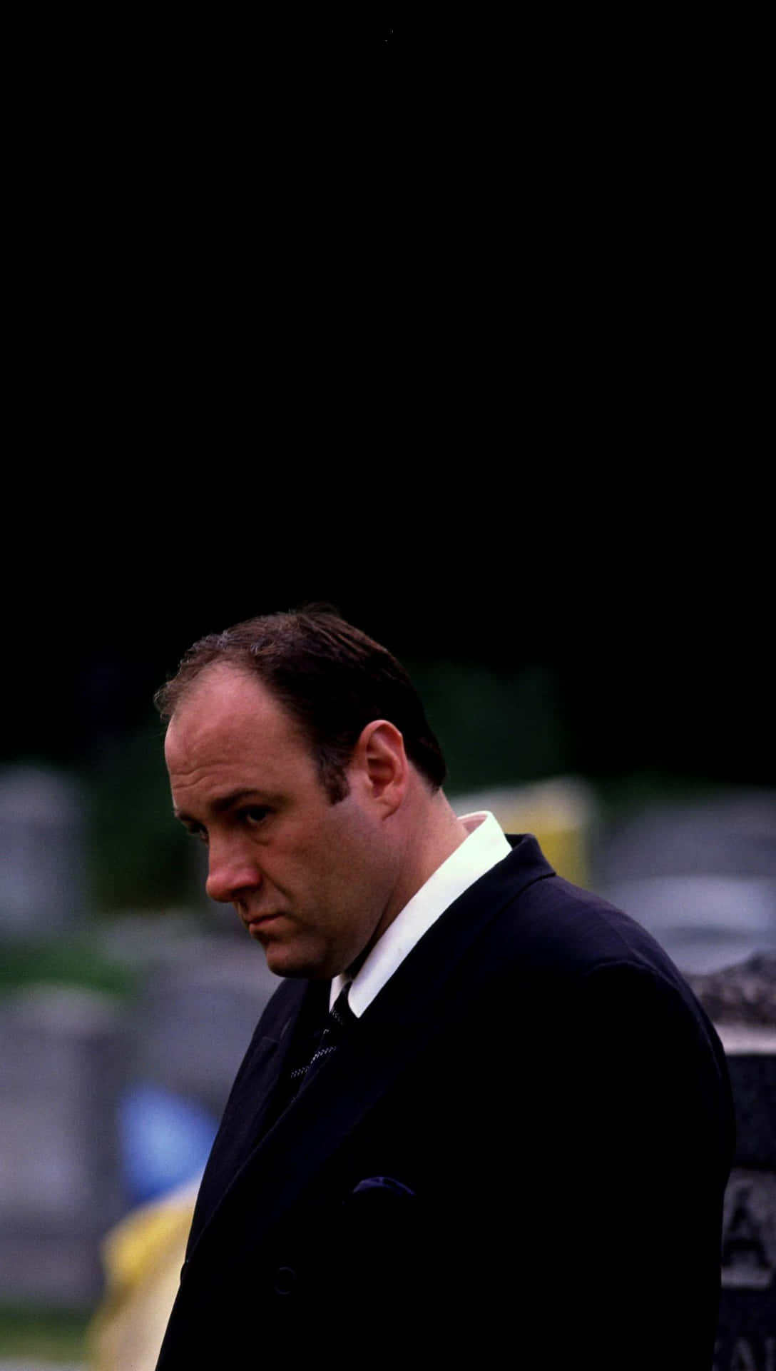 A Man In A Suit Standing In A Cemetery