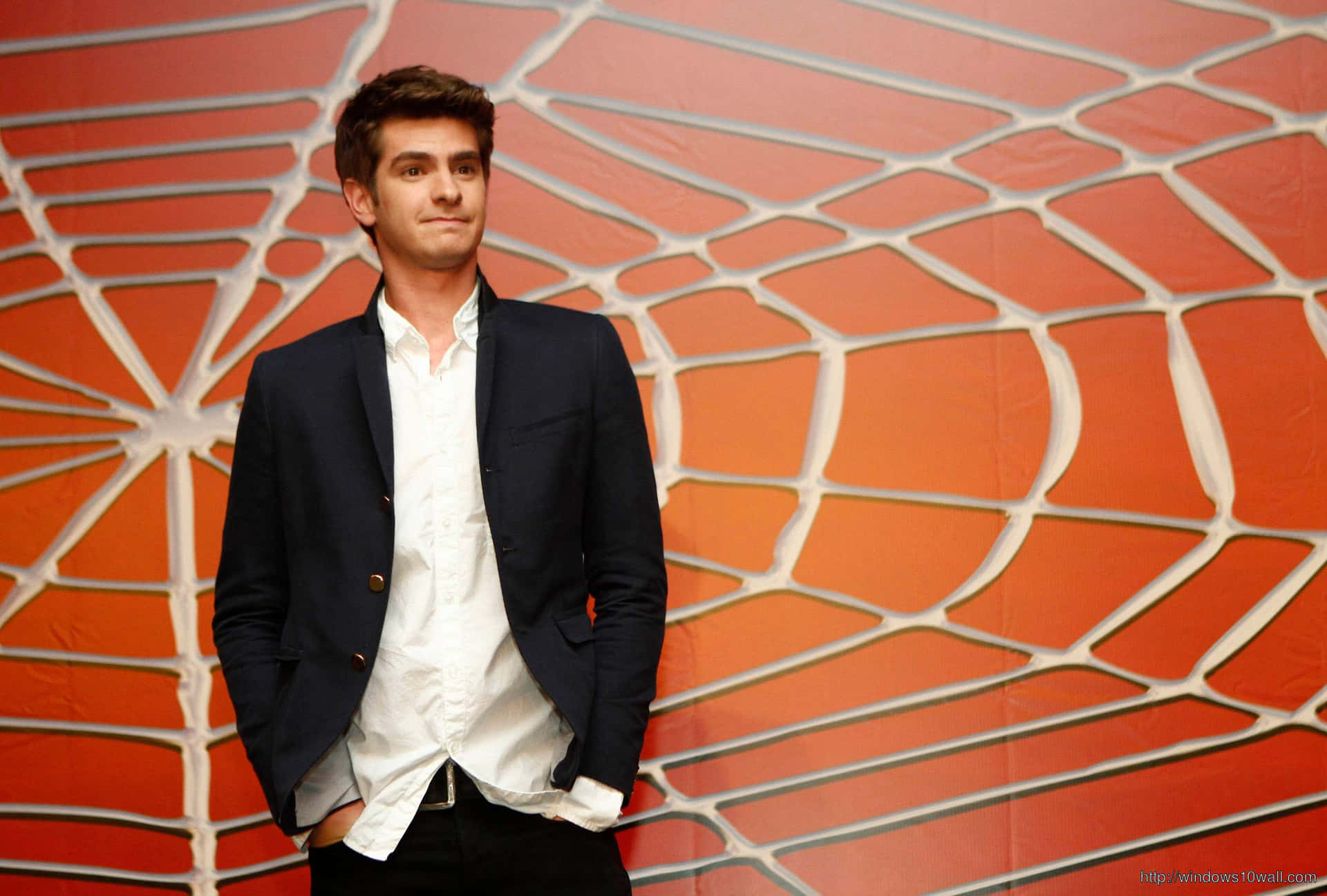 A Man In A Suit Standing In Front Of A Spider Web Background