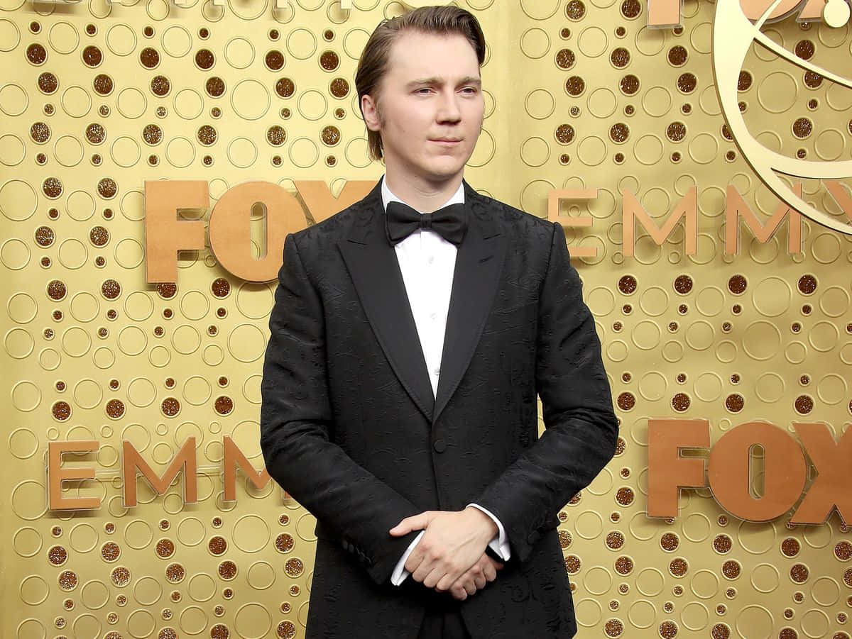 A Man In A Tuxedo Standing On The Red Carpet Background
