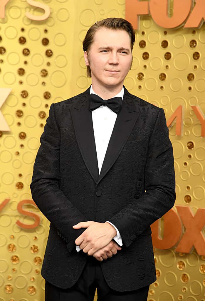 A Man In A Tuxedo Standing On The Red Carpet Background