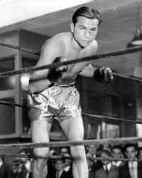 A Man In Boxing Shorts Standing In A Ring Background