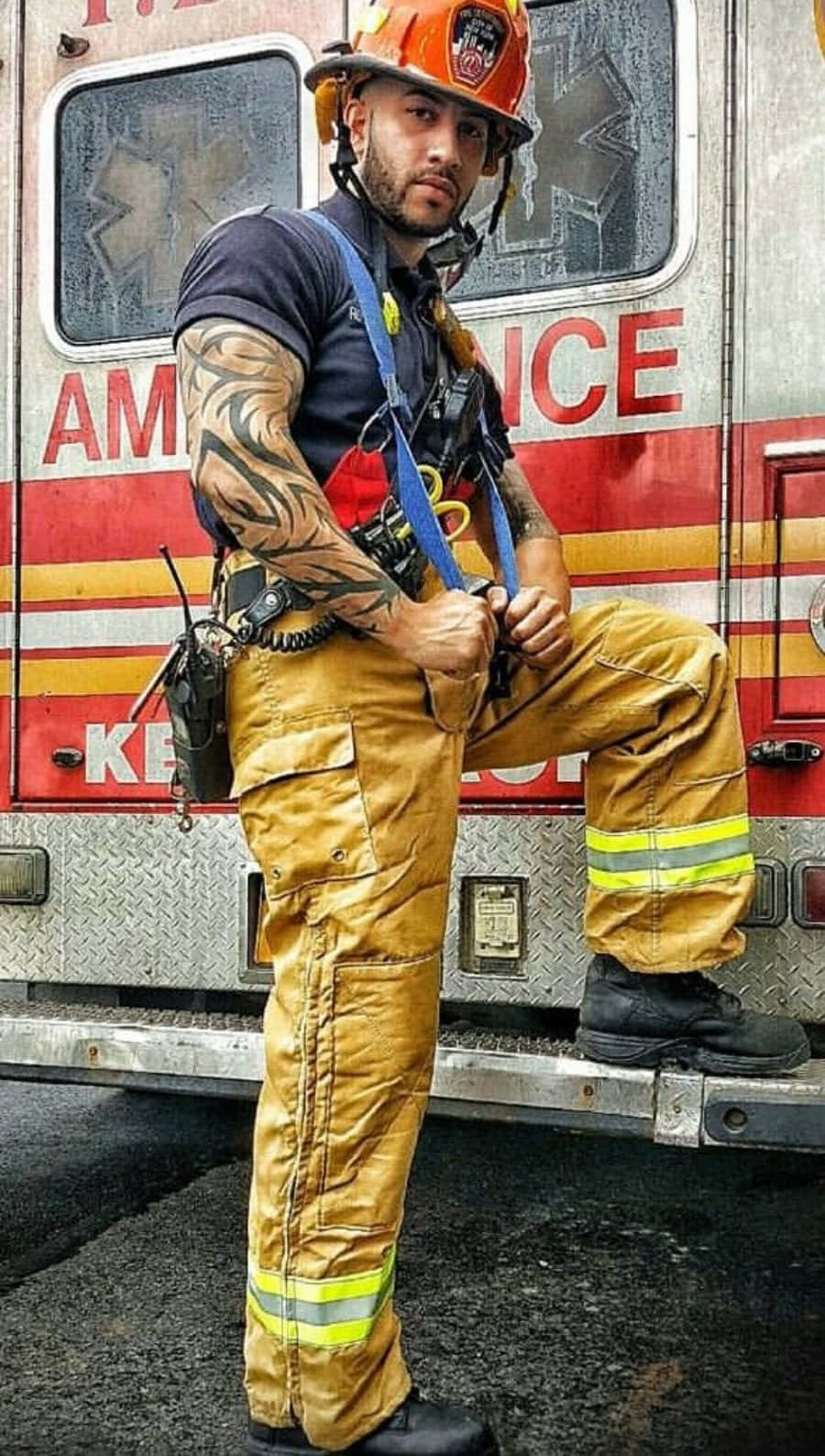 A Man In Firefighter Gear Leaning Against A Truck Background