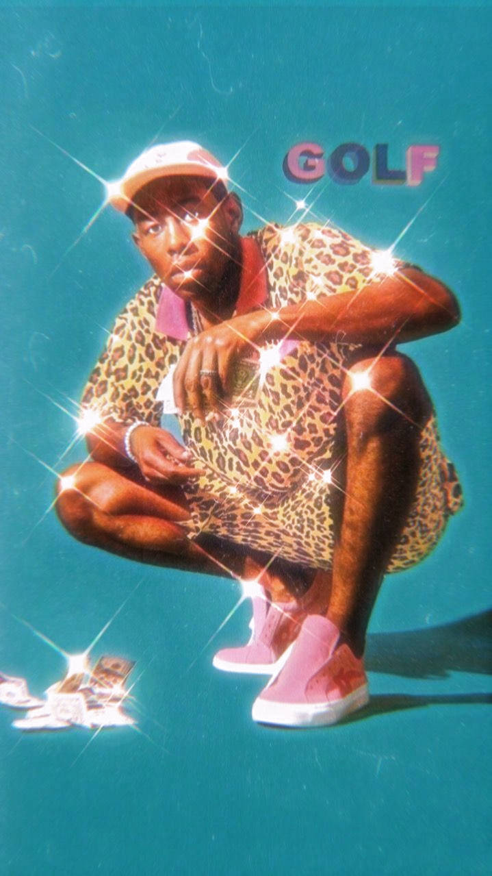 A Man In Leopard Pants Is Kneeling Down With A Golf Ball Background