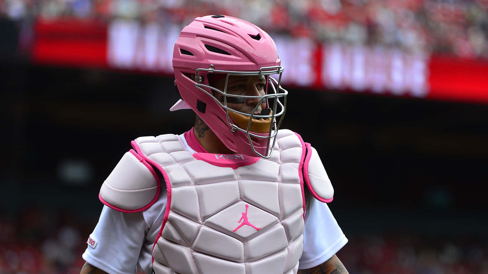 A Man In Pink Baseball Gear Is Standing On A Field Background