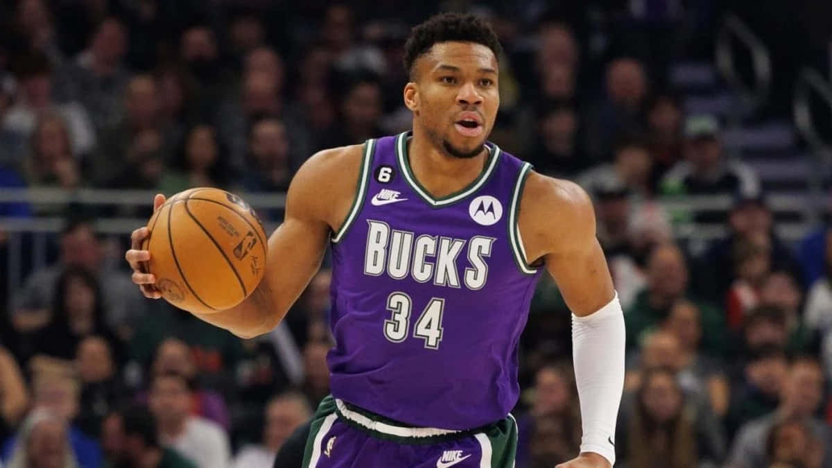 A Man In Purple Uniform Is Holding A Basketball Background