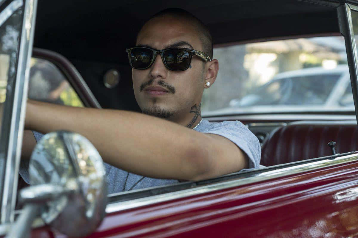 A Man In Sunglasses Driving A Classic Car Background